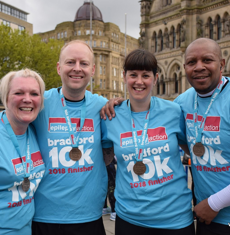Four participants of the Bradford 10k event wearing medals Four participants of the Bradford 10k event wearing medals