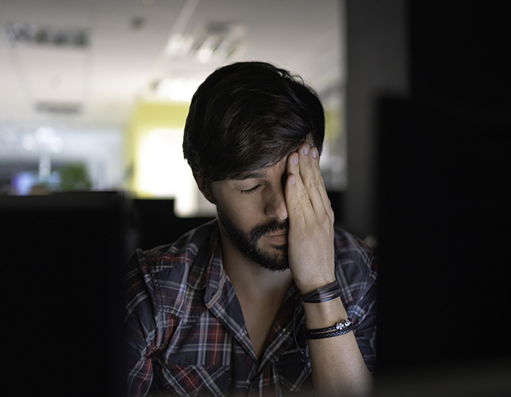 A man holding his head looking tired suggesting the effects of seizure triggers