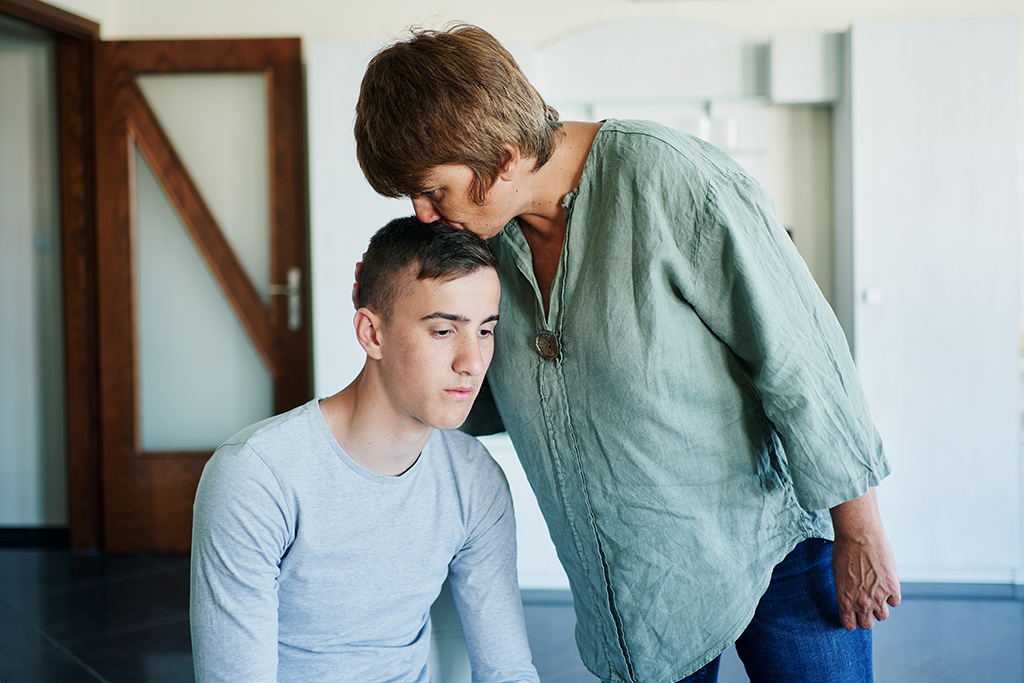 A mother comforts her teenage son. A mother comforts her teenage son.