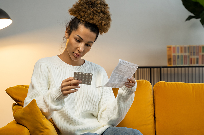 Woman reads the instructions for contraception pills