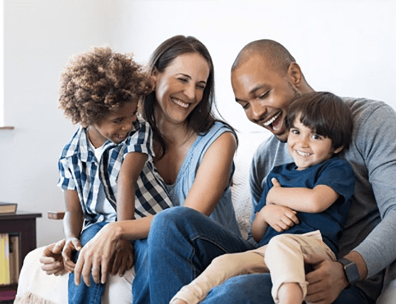 A family sitting on a sofa laughing