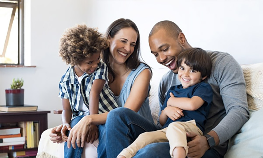 A family sitting on a sofa laughing