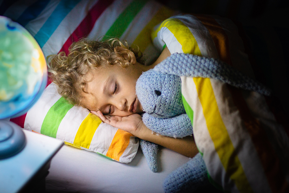A child with epilepsy in bed going to sleep whilst holding their teddy.