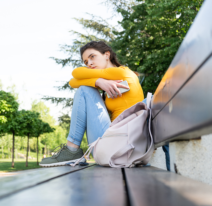 A sad teenager sitting on a park bench