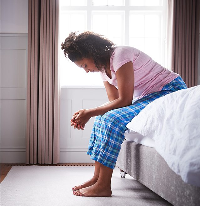 Woman wearing pajamas sitting on a bed