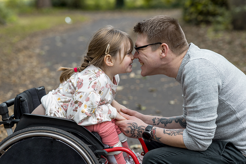 A parent smiling with his child in the park