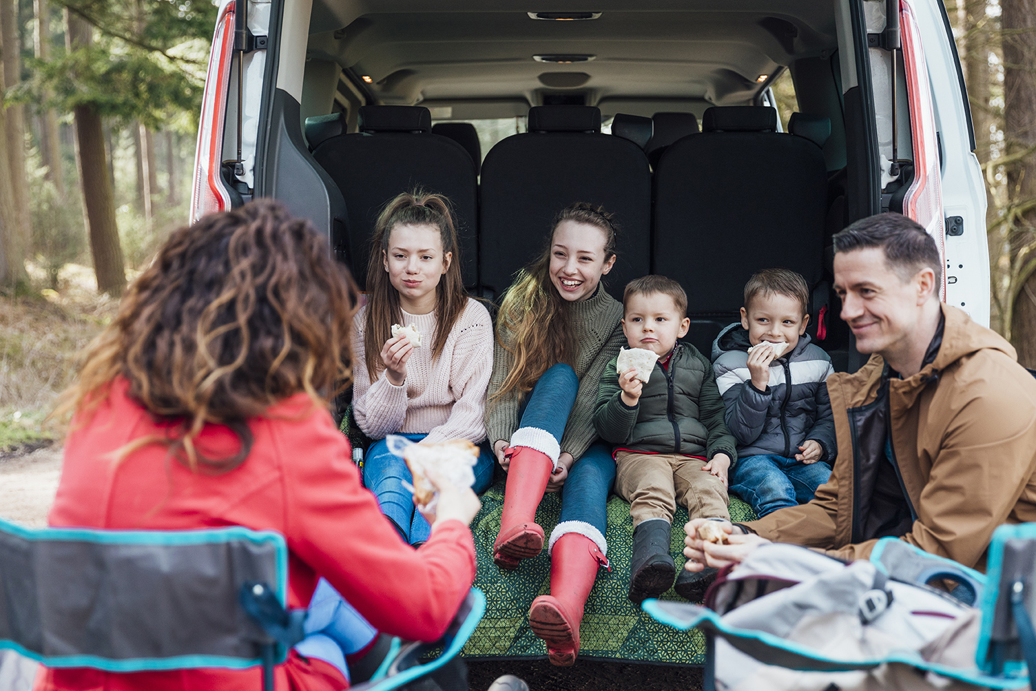 A family eating a picnic together in the back of a van