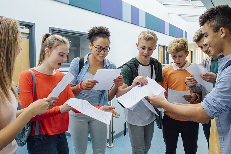 A student with epilepsy with fellow student smiling after recieving exam results