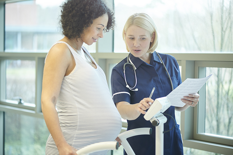 a pregnant lady is weighed by midwife