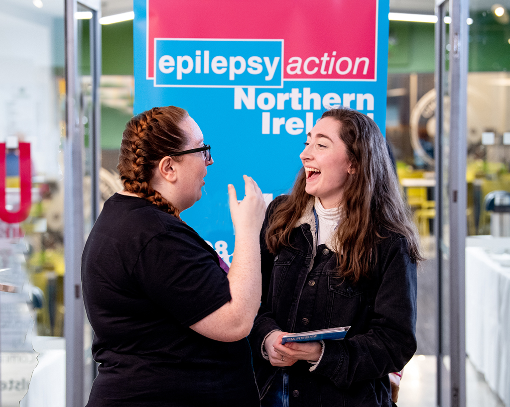 two laughing women, one is holding a just for kids pack