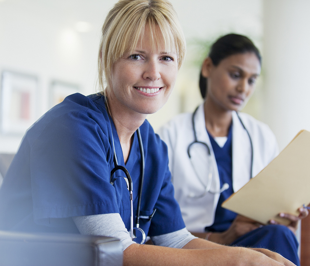 A smiling nurse sitting with doctor in hospital