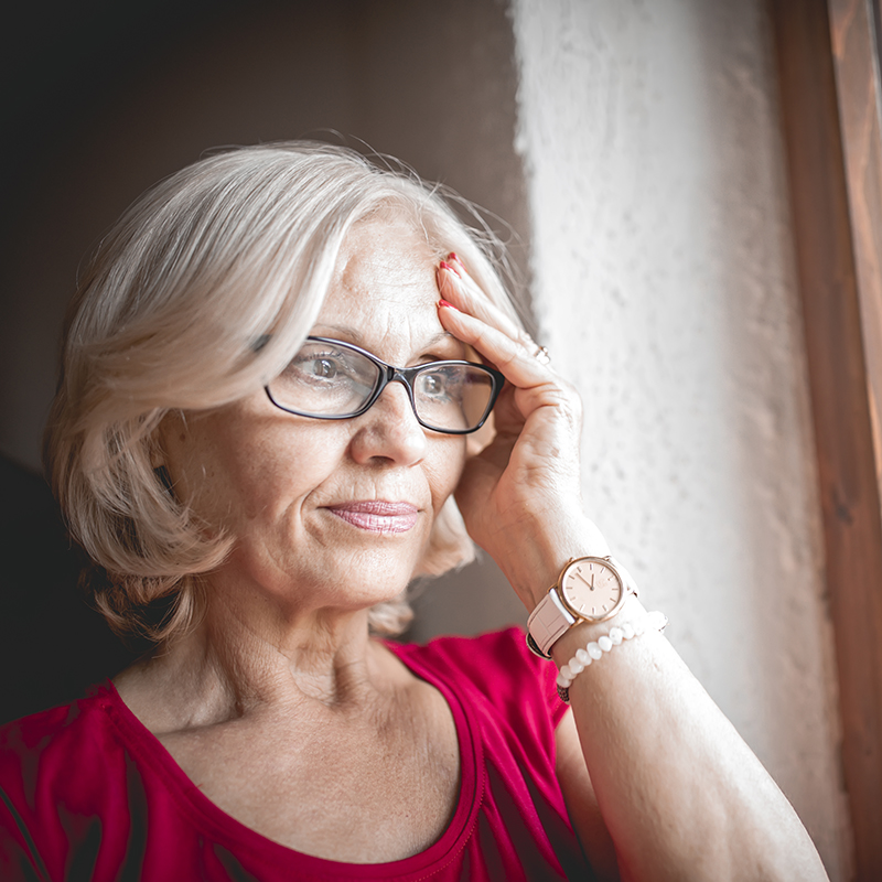 Concerned senior woman looking out of a window