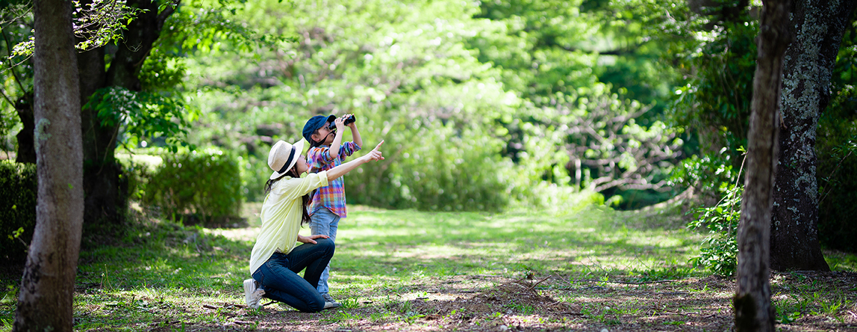 Mother and daughter playing with binoculars in the woods