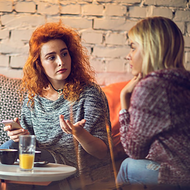 Two young women talking to each other in a café