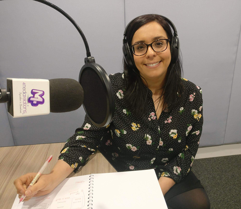 Woman wearing headphones using a microphone and notepad