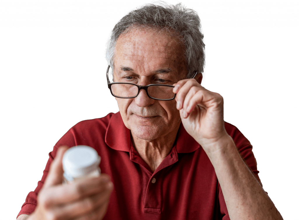 A senior man wearing glasses looking at a bottle of medicine