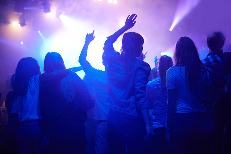 A crowd People enjoying a rock concert with flashing lights in the background