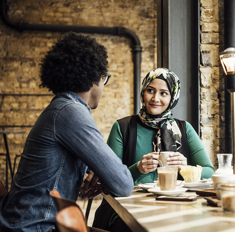 Two multi racial friends enjoying coffee in café