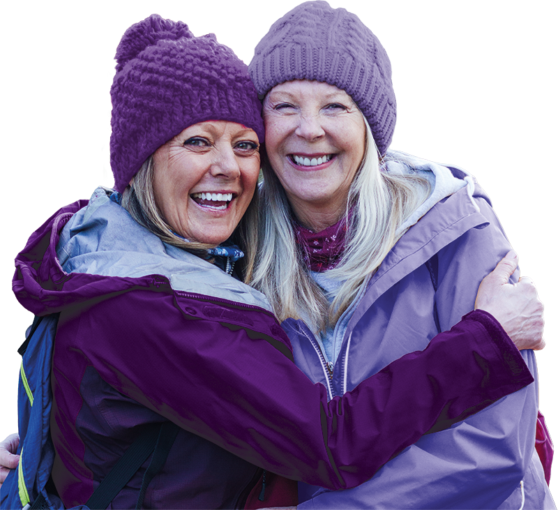 Two ladies dressed in purple, hugging and smiling.