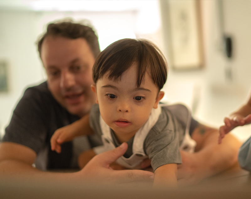 Young child being held by parent, both facing towards camera