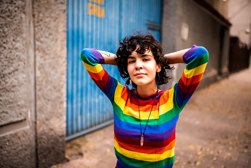 A person standing in the street with a rainbow jumper on