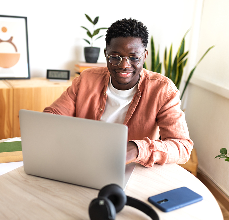 This image depicts a black man using a laptop computer
