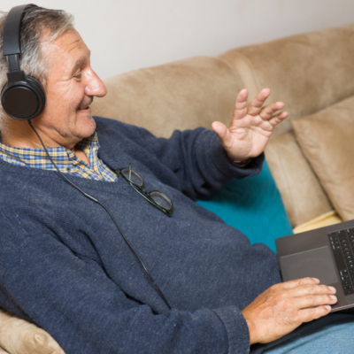 An older man taking part in a video call whilst wearing headphones