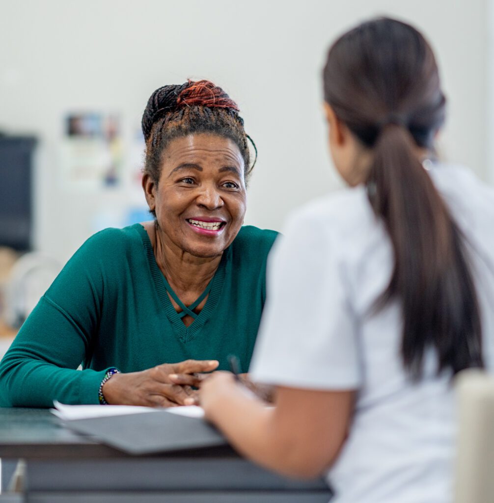 Patient in green top talking to clinician in uniform about their epilepsy treatment and care