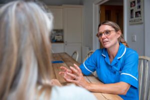 Epilepsy specialist nurse talking about treatment and care to a patient in their kitchen at home