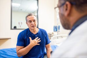 Man sitting on hospital bed talking to doctor about epilepsy treatment and care