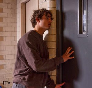 Brody from coronation street, standing in a cell in stc with his hand on the door asking for his epilepsy medication