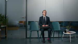 A man sat nervously on a chair outside an office waiting for a job interview
