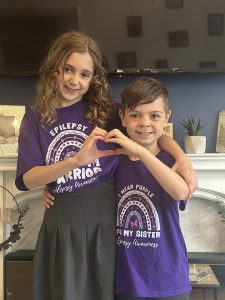 Maddison and her brother posing together and doing a heart shape with their hands