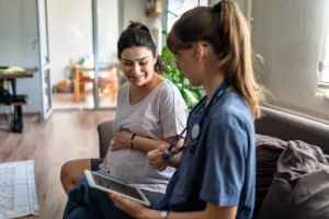 A nurse speaking to a pregnant woman during an appointment. Maternity clinical standards