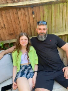 Lyla and Ed sitting on a sofa in the garden. Ed wrote a poem documenting Lyla's journey with epilepsy and shared it for Father's Day