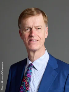 A head and shoulders shot of Sir Stephen Timms wearing a blue suit and a colourful tie