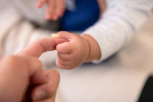 Baby in australia first to receive precision treatment. Close up of a baby's hand holding parent's finger