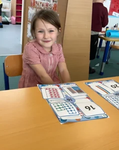 Grace smiling with her maths work at school