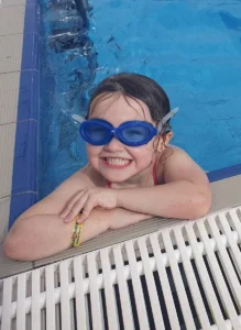 Biscovey Primary Academy Wins July'S Epilepsy Star Award For ‘Exemplary Care’ 3 Grace smiling at the edge of the swimming pool with big blue goggles on