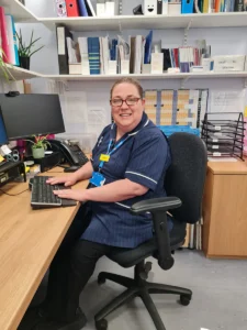 Elaine westall - nurse sitting at her desk smiling