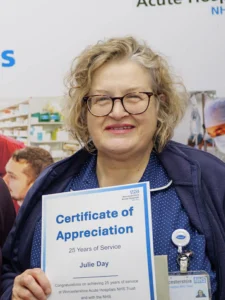 Nurse with blonde curly hair holding a certificate and smiling