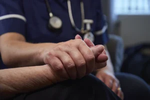 Nurse's hand holding a patient's hand in close up